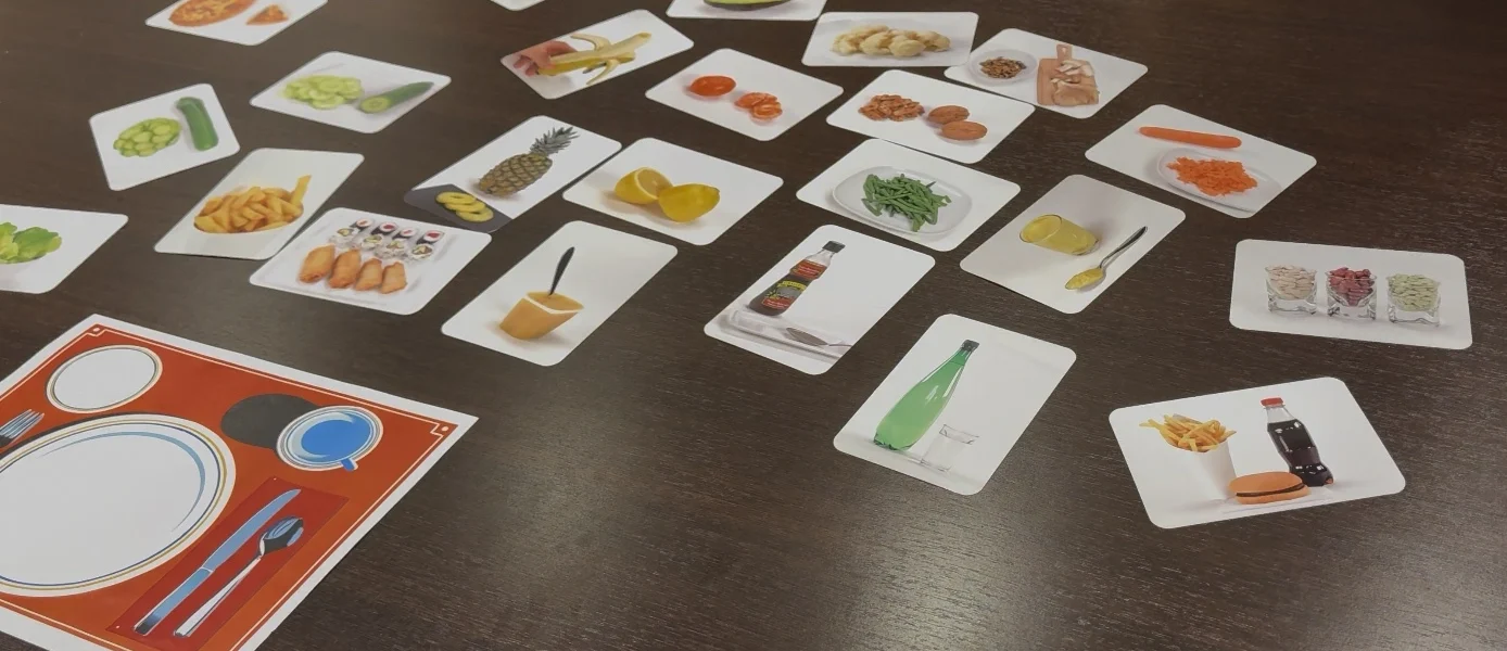 Cartes représentant différents aliments disposées sur une table pour un exercice de composition de repas